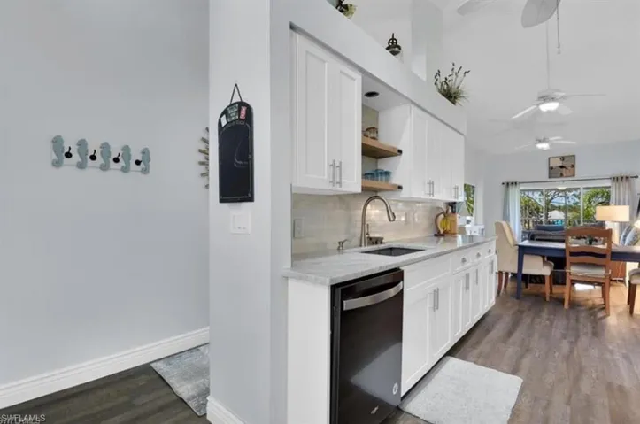 Kitchen with sink, dishwasher, white cabinets, and hardwood / wood-style flooring