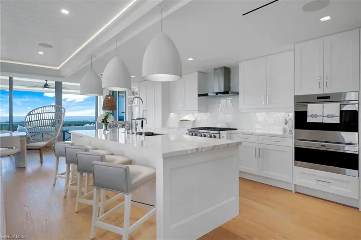 Kitchen featuring decorative backsplash, ceiling fan, white cabinets, light stone counters, and decorative light fixtures