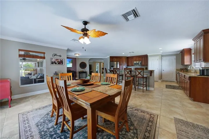 Dining space with light tile patterned floors, ornamental molding, sink, and ceiling fan