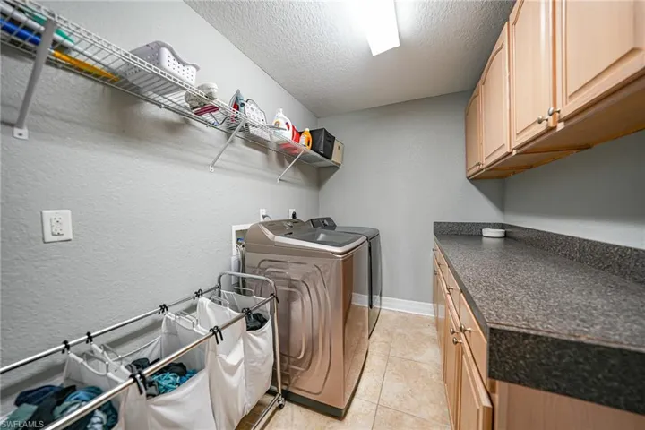 Laundry room on second level featuring a textured ceiling, washer and clothes dryer, and cabinets next to master bedroom