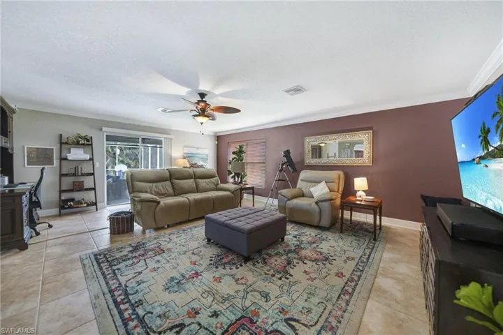 Tiled living room featuring a textured ceiling, crown molding, and ceiling fan
