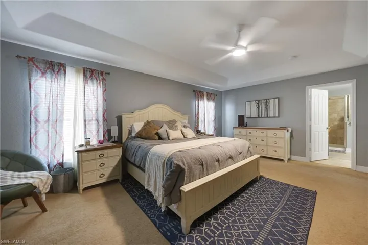Carpeted bedroom featuring ceiling fan and ensuite bathroom