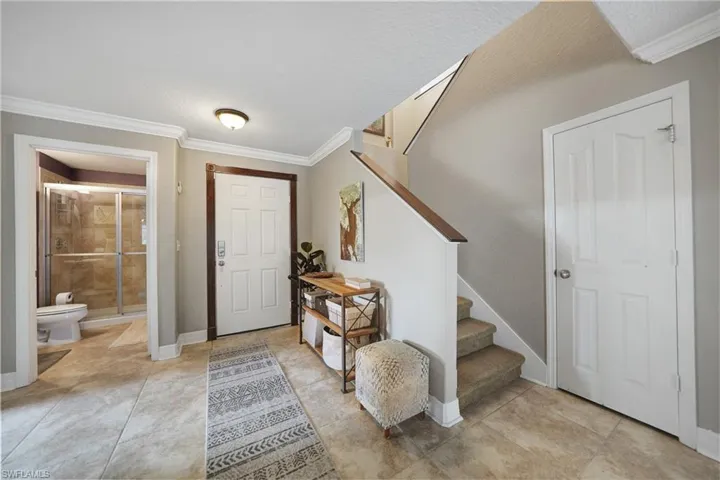 Foyer entrance featuring a textured ceiling and ornamental molding