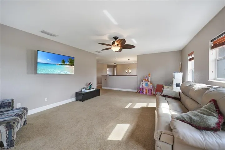 Carpeted loft room with ceiling fan with notable chandelier
