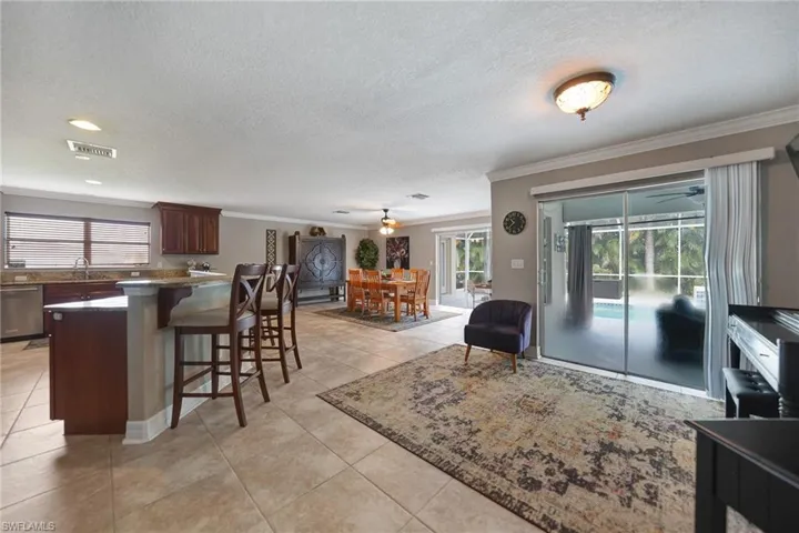 Tiled living room featuring a textured ceiling, crown molding, and ceiling fan