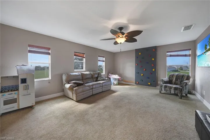 Loft with ceiling fan and light colored carpet