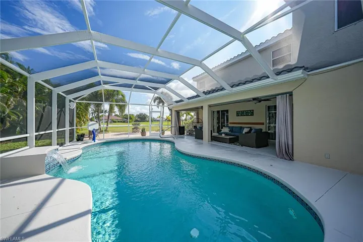 View of pool featuring ceiling fan, a patio area, pool water feature, an outdoor living space, and glass enclosure