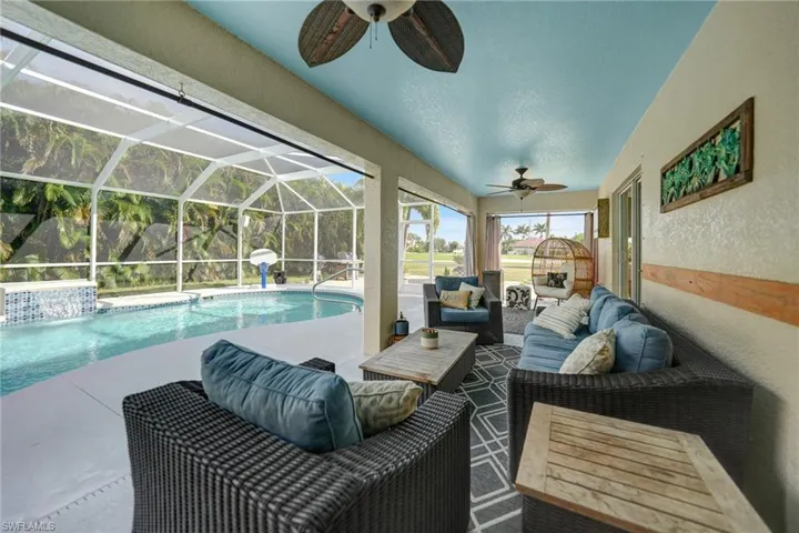 View of pool with ceiling fan, an outdoor living space, glass enclosure, and a patio area
