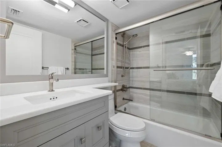 Full bathroom featuring shower / bath combination with glass door, vanity, and toilet