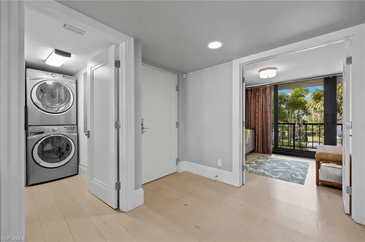 Laundry room featuring light wood-type flooring and stacked washer and dryer