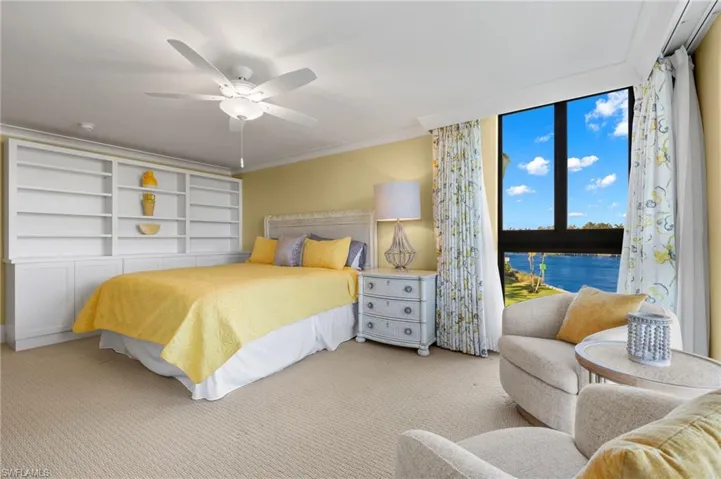 Carpeted bedroom featuring a water view, ceiling fan, and ornamental molding