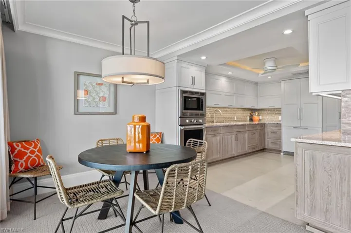 Dining room with ceiling fan, a raised ceiling, ornamental molding, and sink