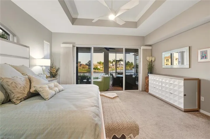 Master Bedroom featuring access to outside, carpet, a tray ceiling, ceiling fan, and crown molding walkout to lanai seating area