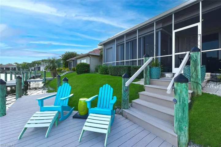 Wooden deck featuring a lawn, a boat dock, and a sunroom