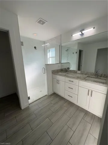 Bathroom featuring a stall shower, double vanity, and wood tiled floors