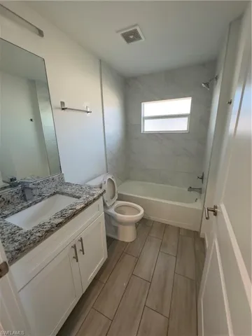Bathroom with vanity,  shower combination, and wood finish floors