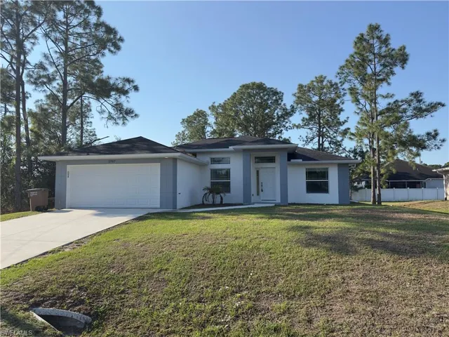 View of front of property featuring an attached garage, stucco siding, driveway, and a front yard