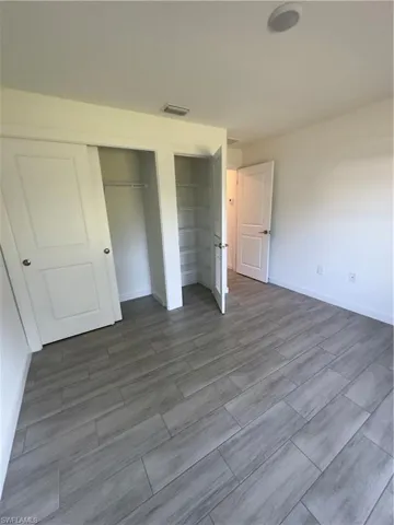 Unfurnished bedroom with multiple closets and wood tiled floors