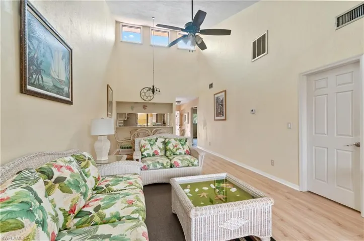 Living room featuring light hardwood / wood-style flooring, a high ceiling, and ceiling fan