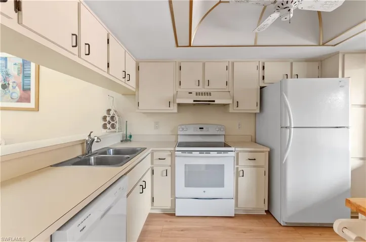 Kitchen with ceiling fan, sink, white appliances, and light wood-type flooring