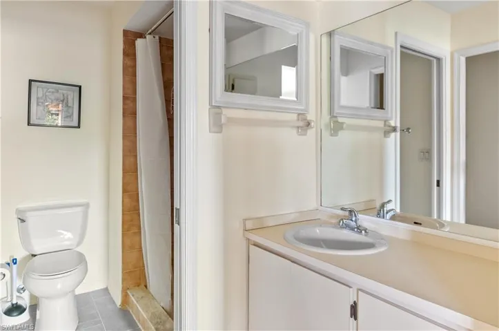 Bathroom with toilet, vanity, a shower with curtain, and tile patterned flooring
