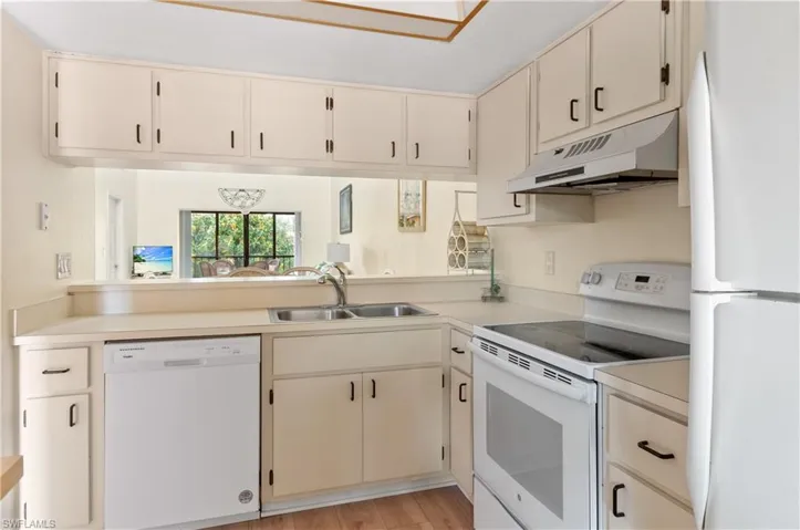 Kitchen with sink, white appliances, and light wood-type flooring