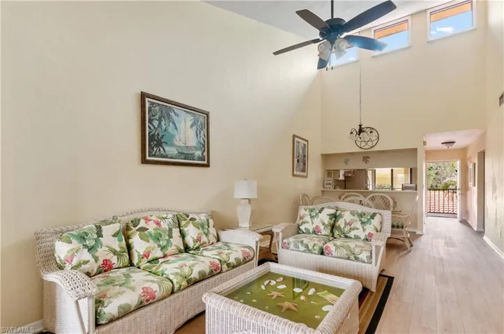 Living room featuring ceiling fan, wood-type flooring, and a towering ceiling