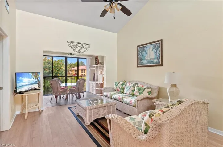 Living room with light wood-type flooring, ceiling fan, and high vaulted ceiling