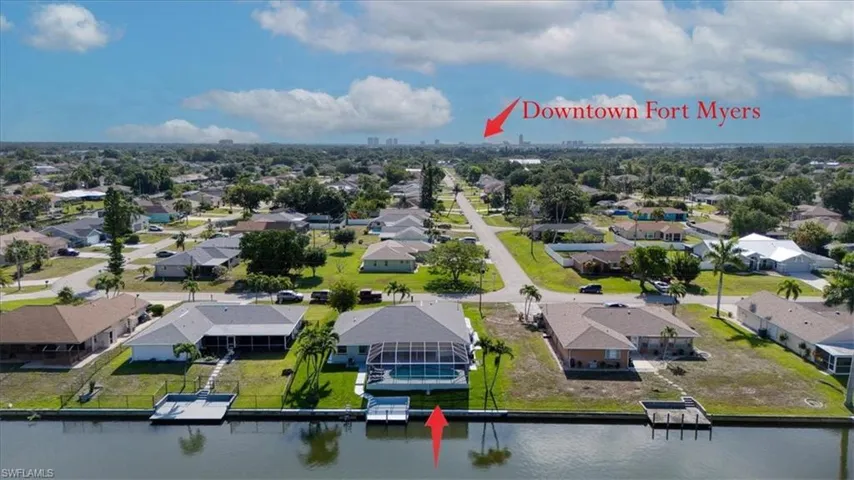Waterfront property featuring a private boat dock, screened swimming pool, and mature palm trees