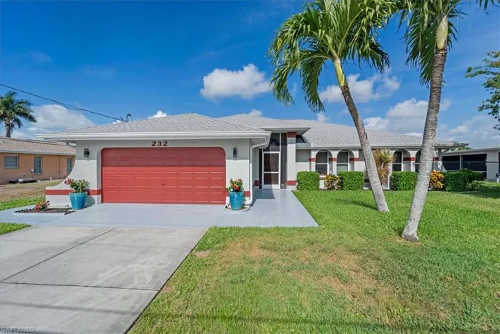 Single-story residence featuring a red garage door, an asphalt driveway, and a concrete walkway