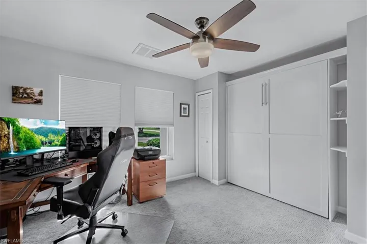 Room featuring a built-in wall unit with shelving, light gray wall paint, and a ceiling fan with integrated lighting