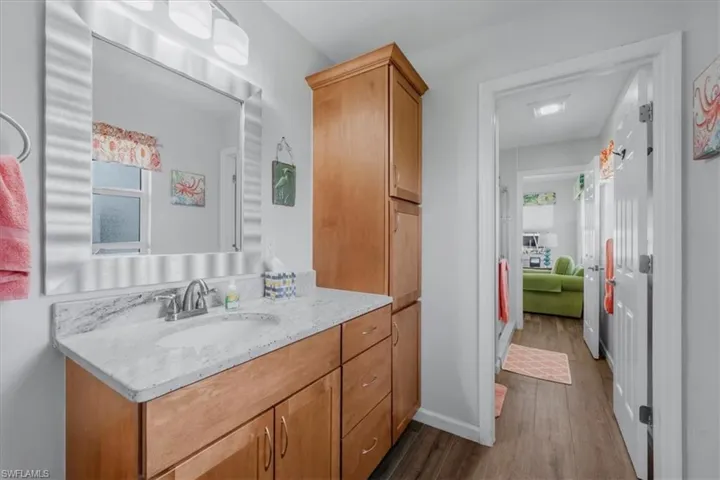 Bathroom vanity with a light-toned countertop, integrated sink, and chrome faucet