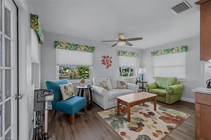 Living area with wood look tile flooring, white walls, and a ceiling fan