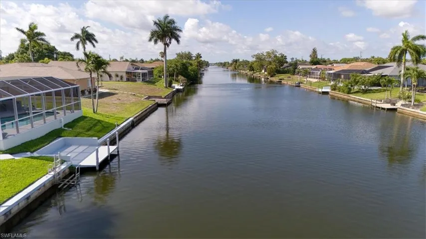 Waterfront property featuring a private boat dock, screened-in pool enclosure, and mature palm trees with Long canal views.