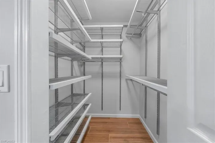 Walk-in closet featuring wood look Tile flooring, adjustable wire shelving, and multiple hanging rods for customized organization