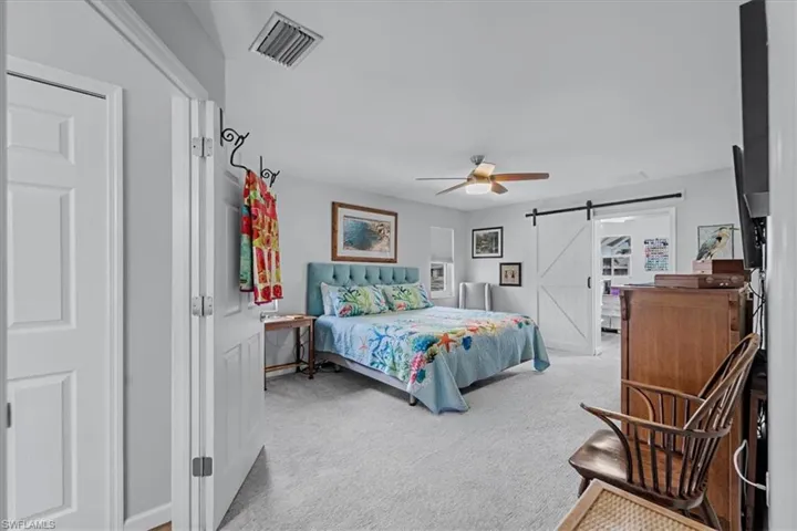 Spacious room featuring light-colored carpeting, a ceiling fan, and a contemporary barn door