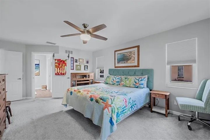 Carpeted room featuring a ceiling fan with light fixture, two windows with blinds, and white paneled doors