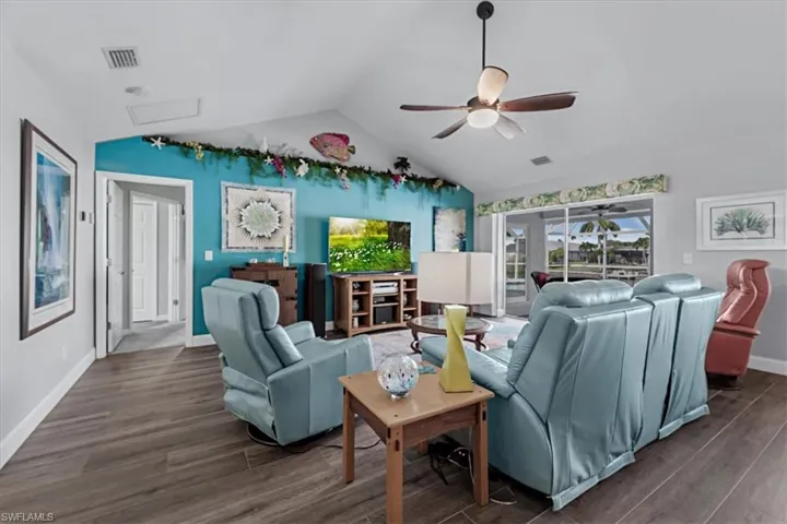 Spacious living area featuring vaulted ceilings, wood look Tile flooring, and a ceiling fan with integrated lighting