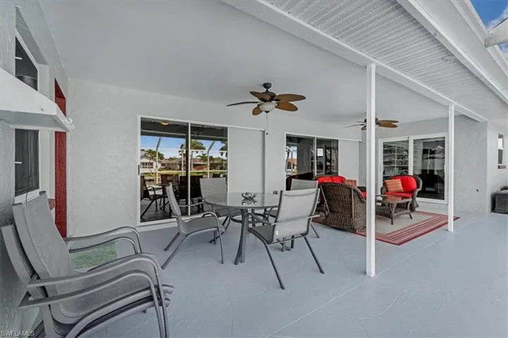 Spacious covered patio featuring multiple ceiling fans, recessed lighting, and a durable gray-toned floor finish