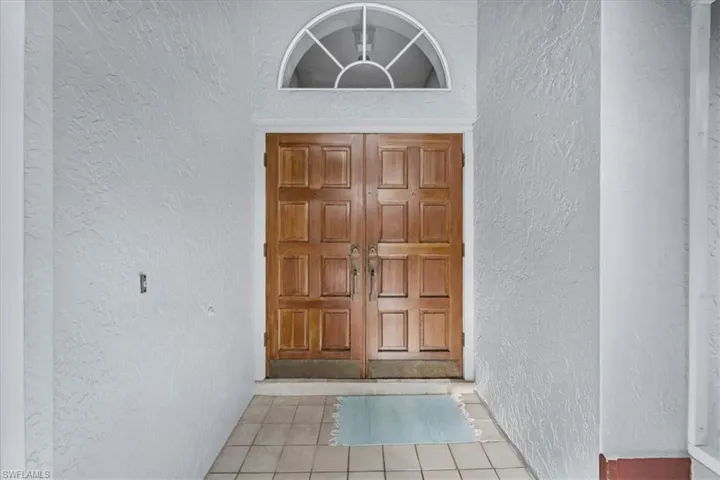 Double wooden entry doors with panel details, complemented by a decorative arched transom window