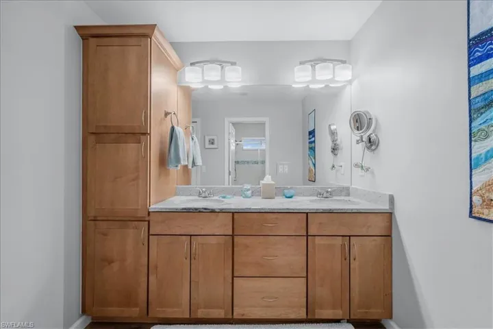 Double vanity featuring light wood-finish cabinetry, a stone countertop, and two undermount sinks