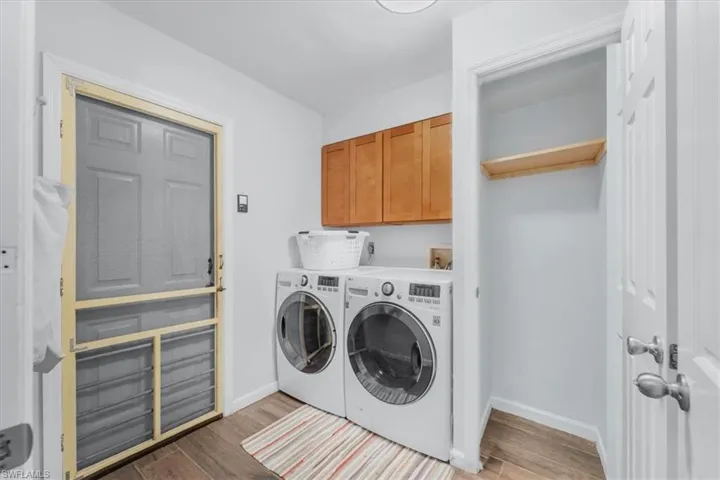 Dedicated laundry area featuring wood look tile flooring, light wood cabinetry, and a utility closet with a built-in shelf