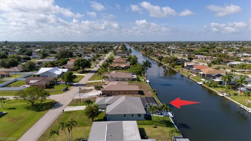 Waterfront property featuring a screened enclosure, private dock, and manicured lawn