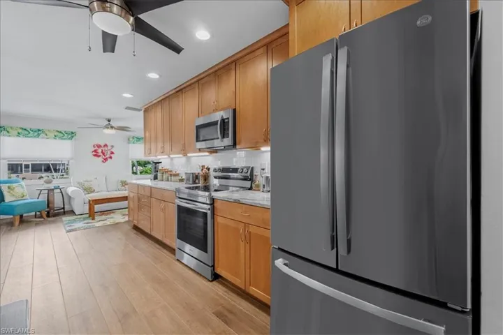 Kitchen featuring light wood cabinetry, stainless steel appliances, a white tile backsplash, and light-toned countertops & Under Cabinet Lighting