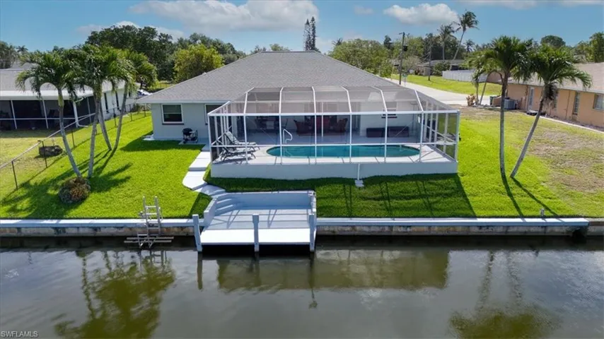Waterfront property featuring a private boat dock, screened-in swimming pool, and a spacious pool deck