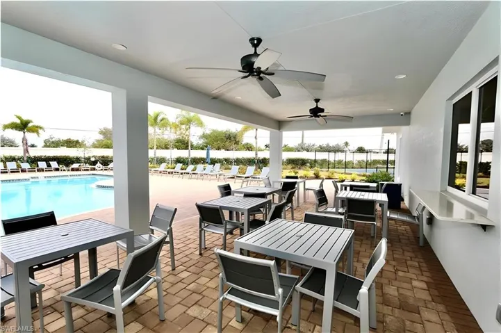View of patio featuring outdoor dining space, a ceiling fan, a community pool, and a water view
