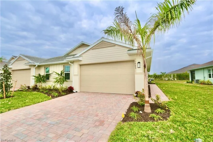 View of front of house featuring a front lawn, decorative driveway, a garage, and stucco siding