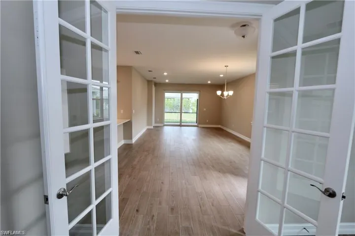 Spare room with a chandelier, light wood-style flooring, french doors, and recessed lighting