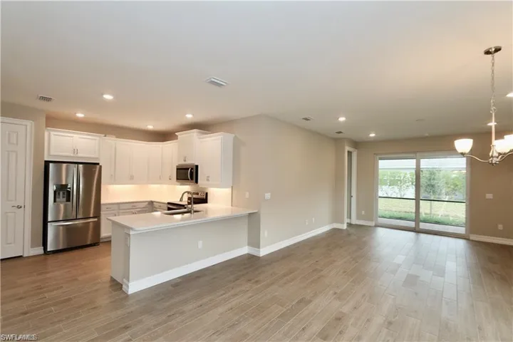 Kitchen featuring appliances with stainless steel finishes, white cabinets, decorative light fixtures, recessed lighting, and a chandelier