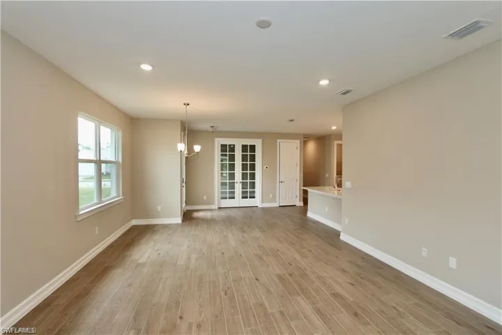 Unfurnished living room with recessed lighting, light wood-type flooring, a chandelier, and french doors